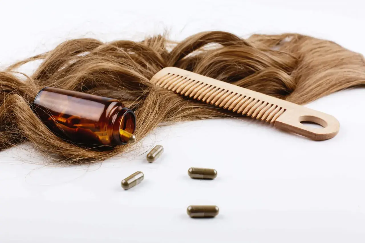 Cabello castaño, peine de madera y cápsulas. El zinc es bueno para el pelo, promoviendo su salud y crecimiento.
