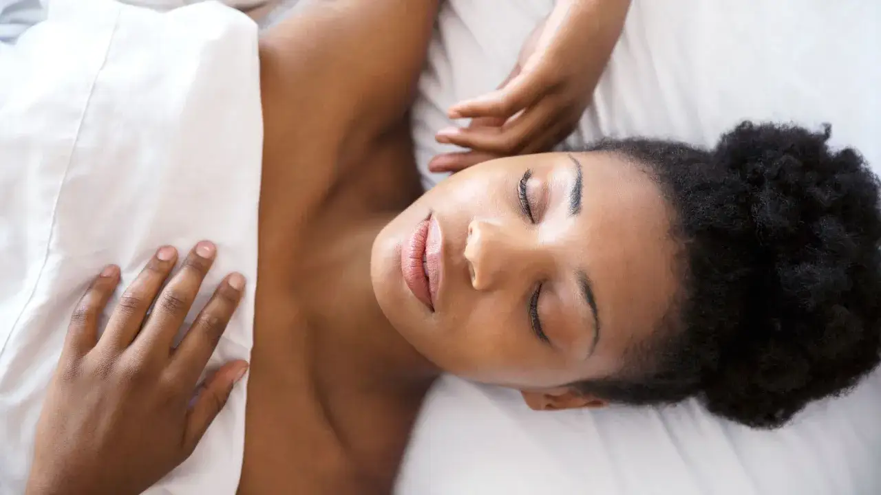 Mujer durmiendo con el pelo recogido en un moño. La pregunta es si es mejor dormir con el pelo suelto o recogido.