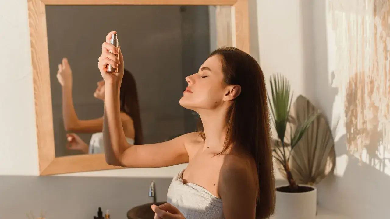 Mujer se rocía bruma facial para refrescar e hidratar su piel. Descubre para qué sirve la bruma facial y cómo puede mejorar tu rutina de cuidado.
